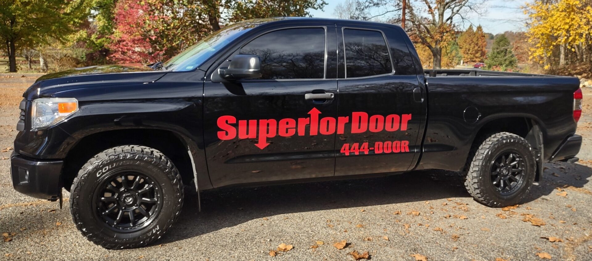 Black truck with Superior Door company logo and phone number on the door.